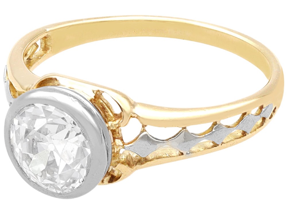 An antique 15ct yellow gold solitaire ring featuring a bezel-set round diamond with decorative openwork shoulders. View VI