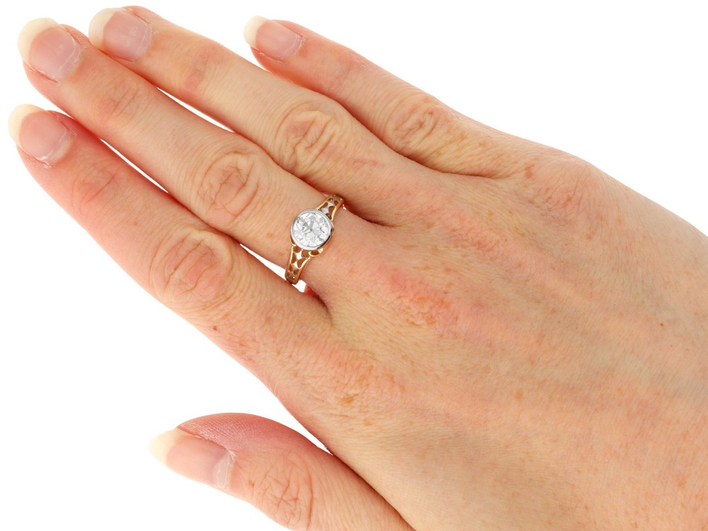 An antique 15ct yellow gold solitaire ring featuring a bezel-set round diamond with decorative openwork shoulders. View IX