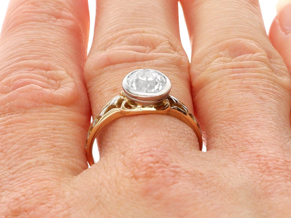 An antique 15ct yellow gold solitaire ring featuring a bezel-set round diamond with decorative openwork shoulders. View XI