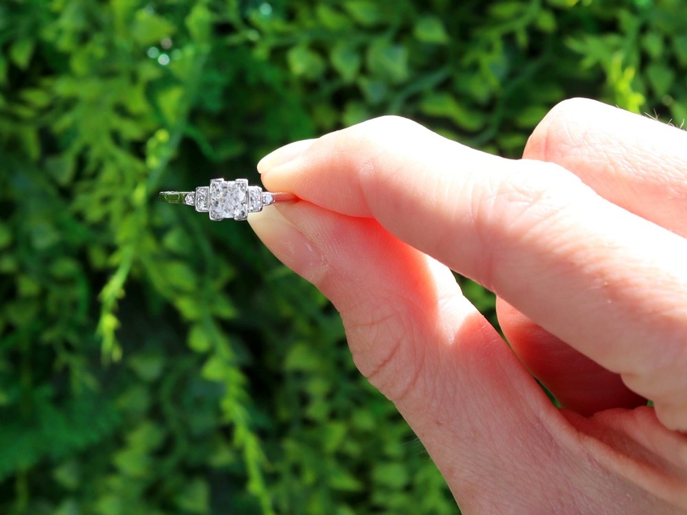 An Art Deco white gold and platinum ring featuring a central round diamond with stepped accent diamond shoulders. View II