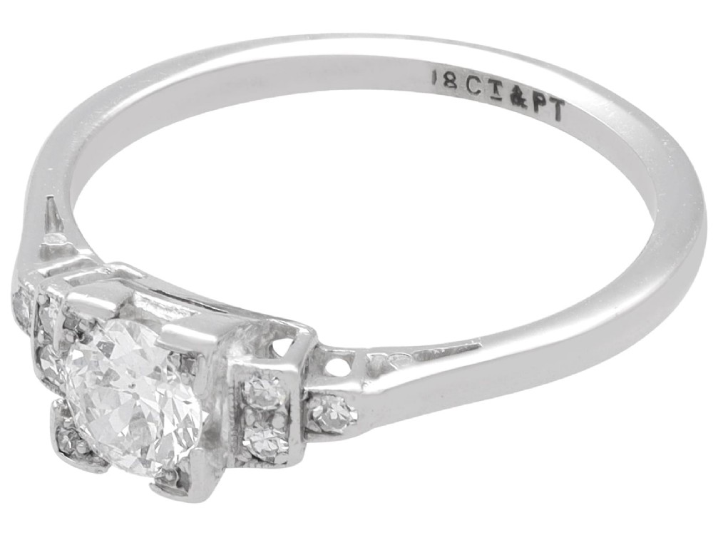 An Art Deco white gold and platinum ring featuring a central round diamond with stepped accent diamond shoulders. View III