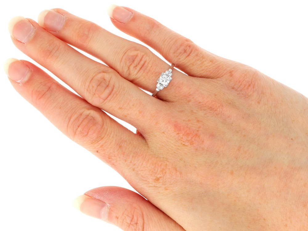 An Art Deco white gold and platinum ring featuring a central round diamond with stepped accent diamond shoulders. View VI