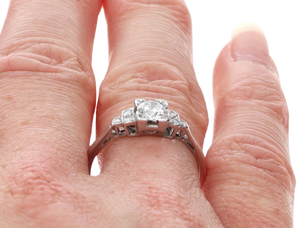 An Art Deco white gold and platinum ring featuring a central round diamond with stepped accent diamond shoulders. View VIII