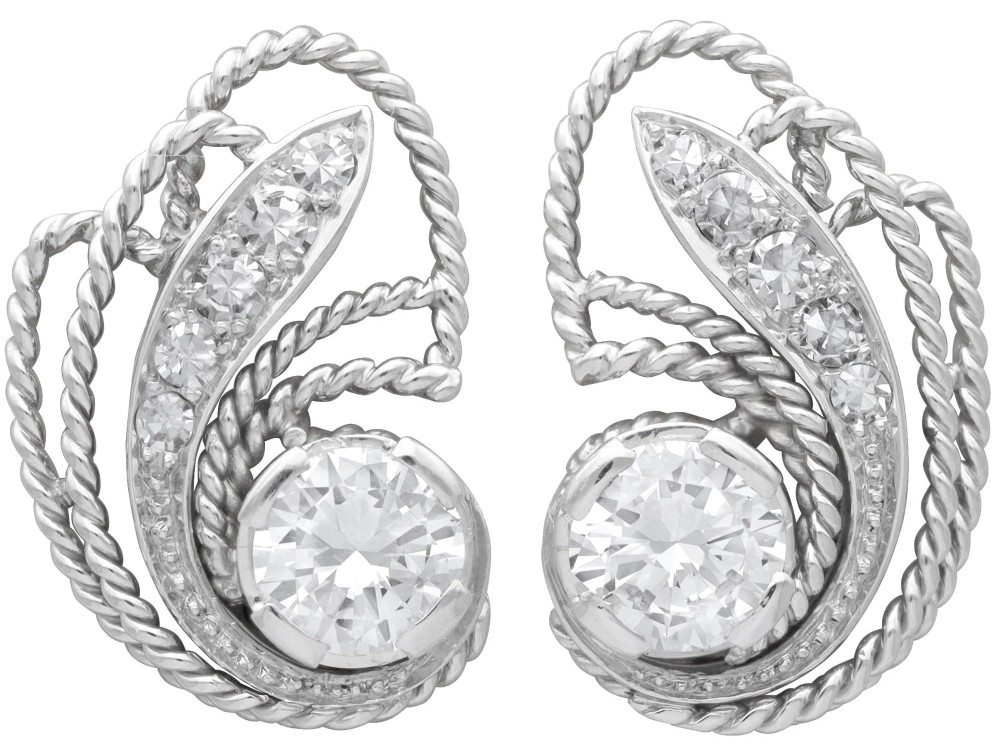 A pair of Art Deco platinum earrings featuring round diamonds set within a textured rope-twist swirl design.
