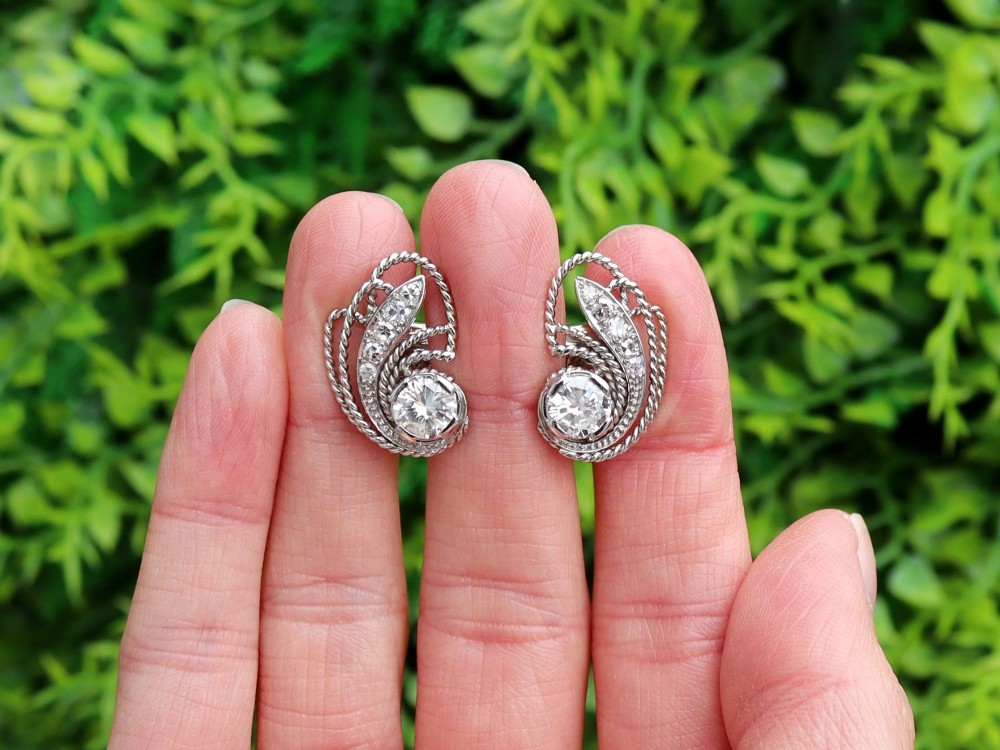 A pair of Art Deco platinum earrings featuring round diamonds set within a textured rope-twist swirl design. View II