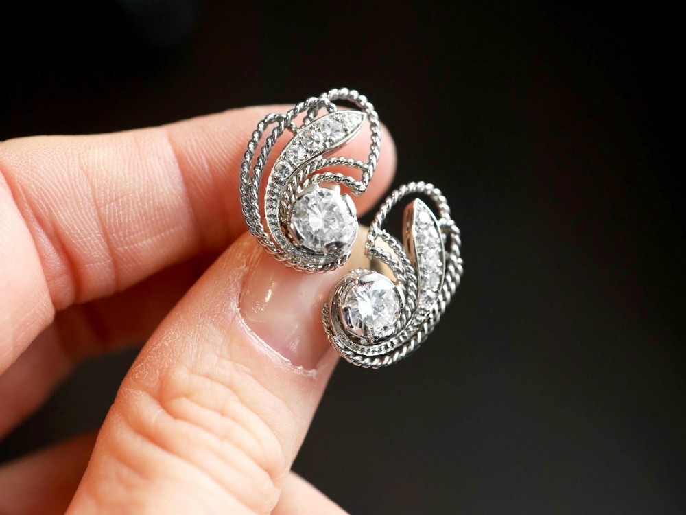 A pair of Art Deco platinum earrings featuring round diamonds set within a textured rope-twist swirl design. View III