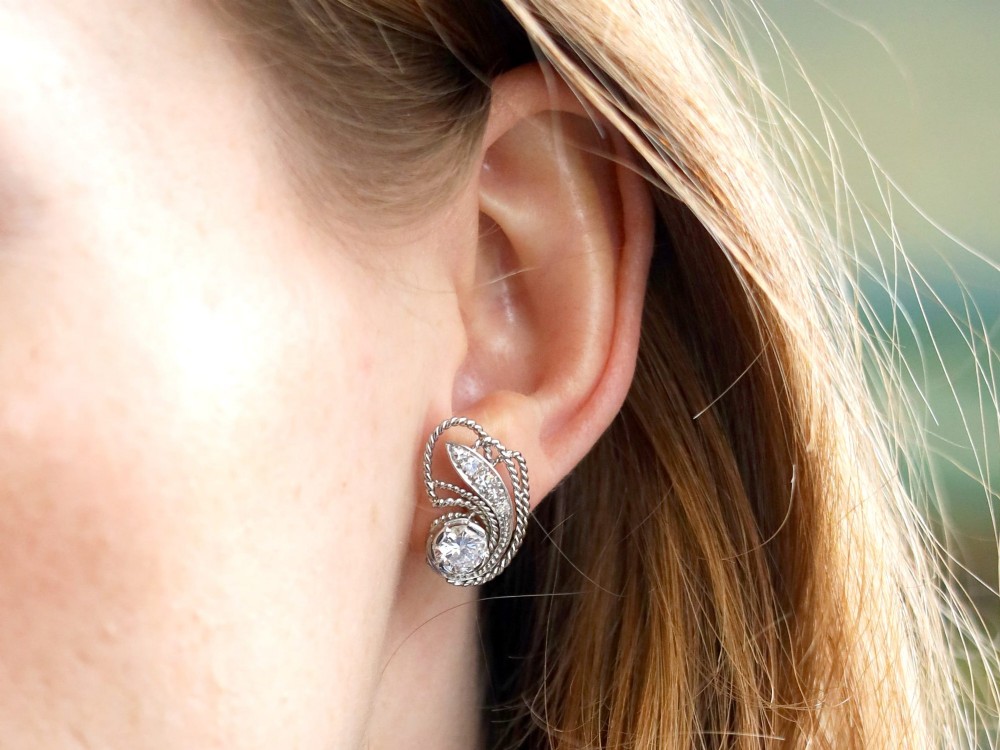 A pair of Art Deco platinum earrings featuring round diamonds set within a textured rope-twist swirl design. View VIII