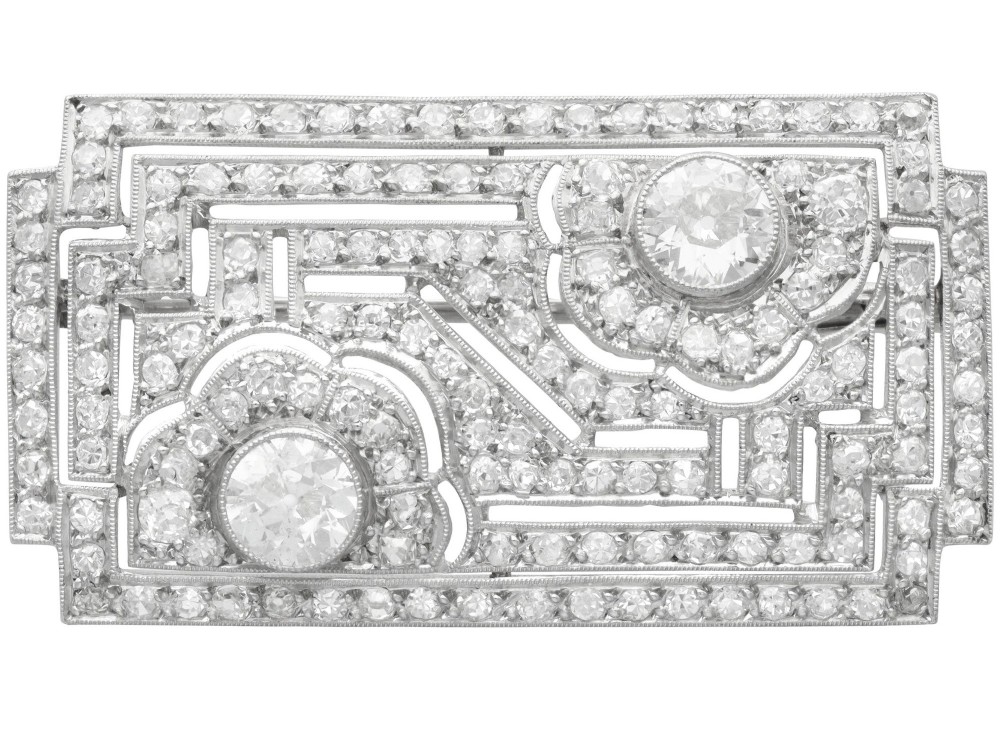 A rectangular Art Deco platinum brooch featuring geometric openwork encrusted with round diamonds and two central bezel-set accent diamonds.