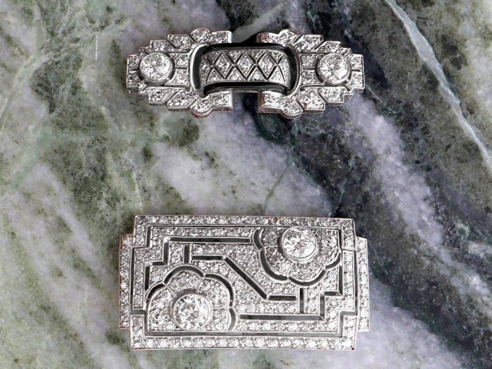 A rectangular Art Deco platinum brooch featuring geometric openwork encrusted with round diamonds and two central bezel-set accent diamonds. View IV