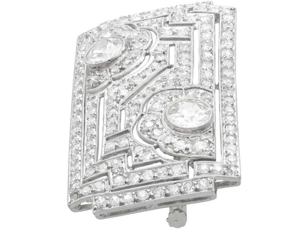 A rectangular Art Deco platinum brooch featuring geometric openwork encrusted with round diamonds and two central bezel-set accent diamonds. View V