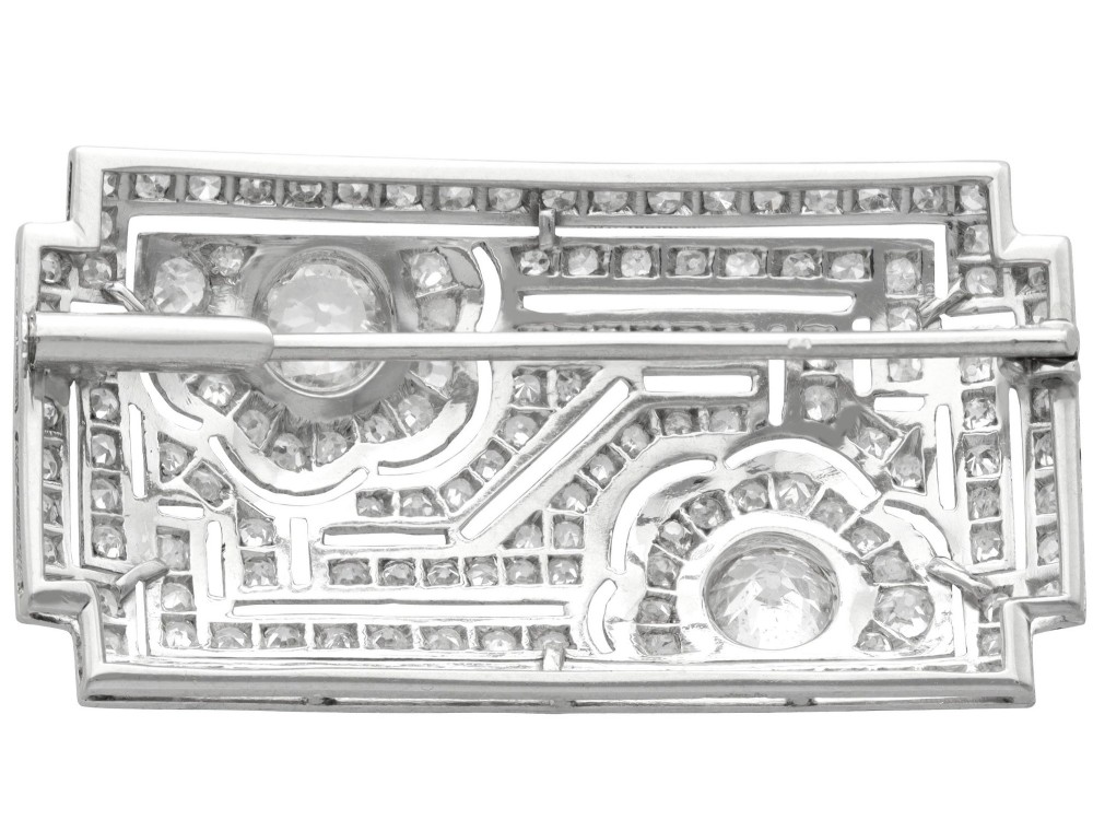 A rectangular Art Deco platinum brooch featuring geometric openwork encrusted with round diamonds and two central bezel-set accent diamonds. View VII