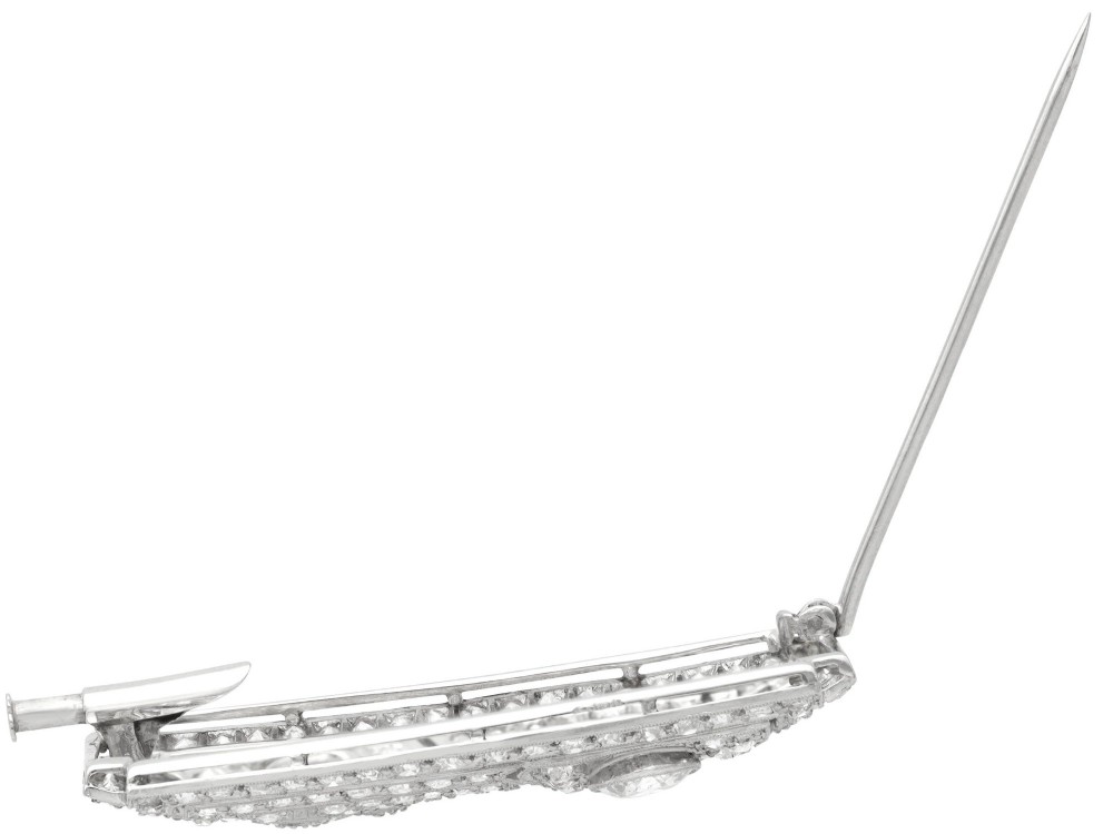 A rectangular Art Deco platinum brooch featuring geometric openwork encrusted with round diamonds and two central bezel-set accent diamonds. View VIII