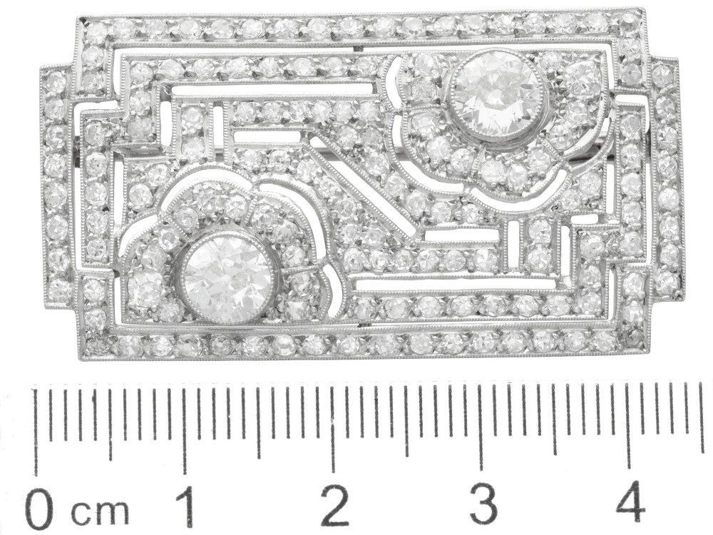 A rectangular Art Deco platinum brooch featuring geometric openwork encrusted with round diamonds and two central bezel-set accent diamonds. View IX