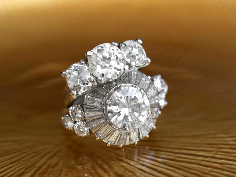 An antique platinum trilogy ring set with three cushion cut diamonds and decorated with hand-engraved shoulders. View VI