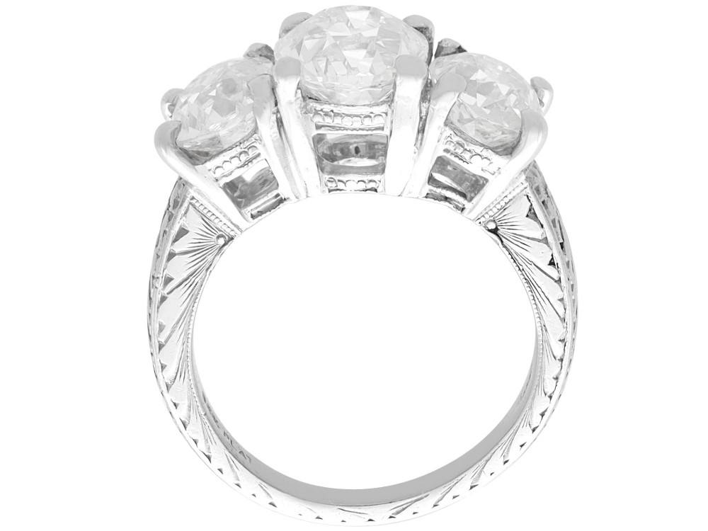 An antique platinum trilogy ring set with three cushion cut diamonds and decorated with hand-engraved shoulders. View IX
