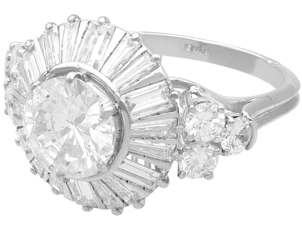 An Art Deco platinum ballerina ring featuring a prominent round central diamond surrounded by a radiating halo of tapered baguette cut diamonds. View VI