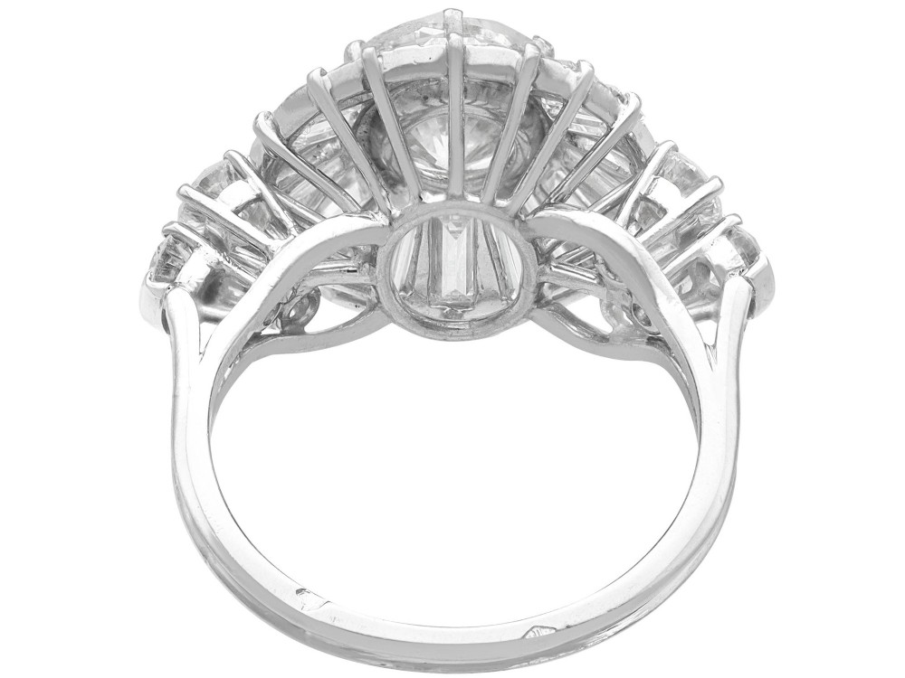 An Art Deco platinum ballerina ring featuring a prominent round central diamond surrounded by a radiating halo of tapered baguette cut diamonds. View VII