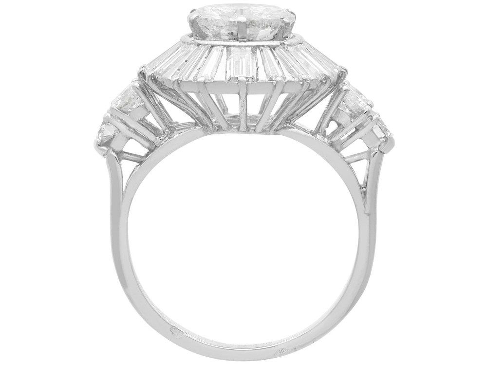 An Art Deco platinum ballerina ring featuring a prominent round central diamond surrounded by a radiating halo of tapered baguette cut diamonds. View VIII