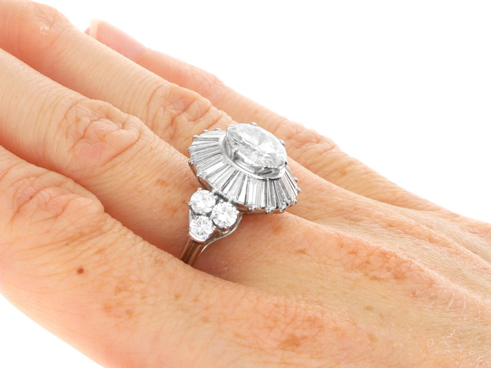 An Art Deco platinum ballerina ring featuring a prominent round central diamond surrounded by a radiating halo of tapered baguette cut diamonds. View X