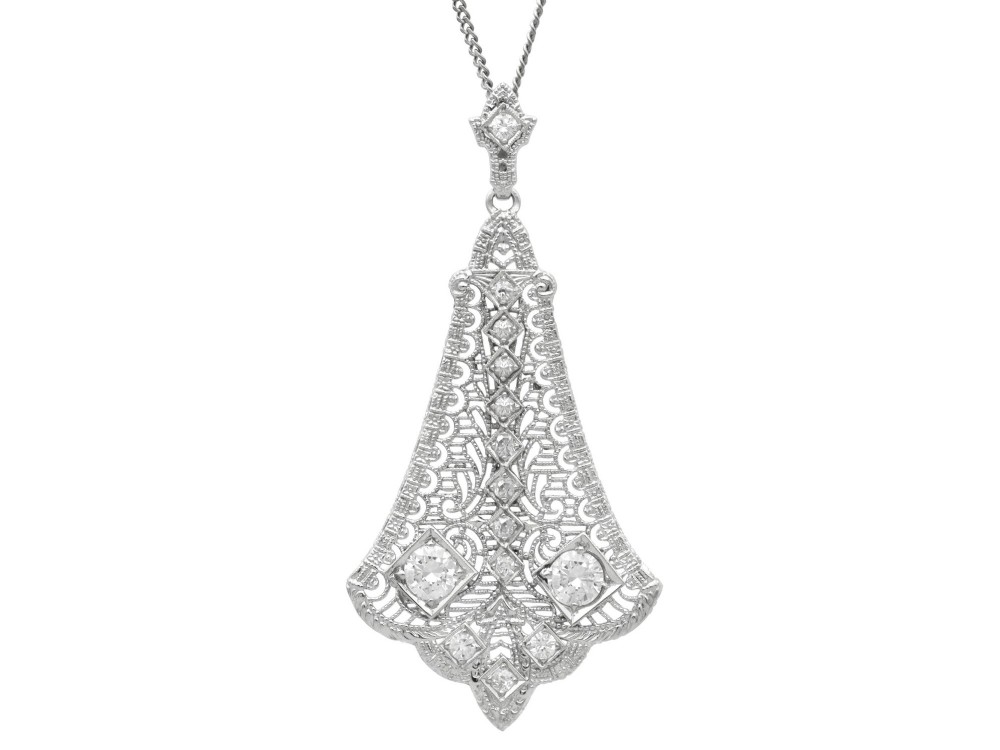 An Art Deco 14ct white gold pendant featuring geometric pierced filigree lattice work set with multiple diamonds suspended from a chain.