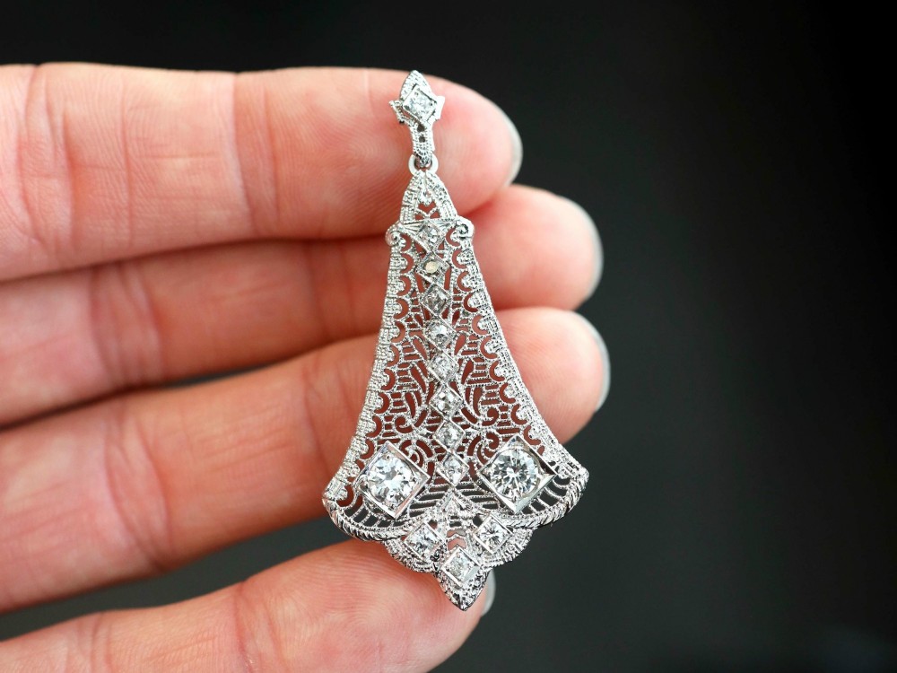 An Art Deco 14ct white gold pendant featuring geometric pierced filigree lattice work set with multiple diamonds suspended from a chain. View V