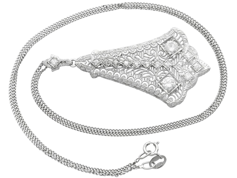 An Art Deco 14ct white gold pendant featuring geometric pierced filigree lattice work set with multiple diamonds suspended from a chain. View VII