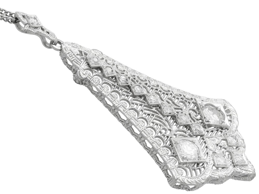 An Art Deco 14ct white gold pendant featuring geometric pierced filigree lattice work set with multiple diamonds suspended from a chain. View VIII