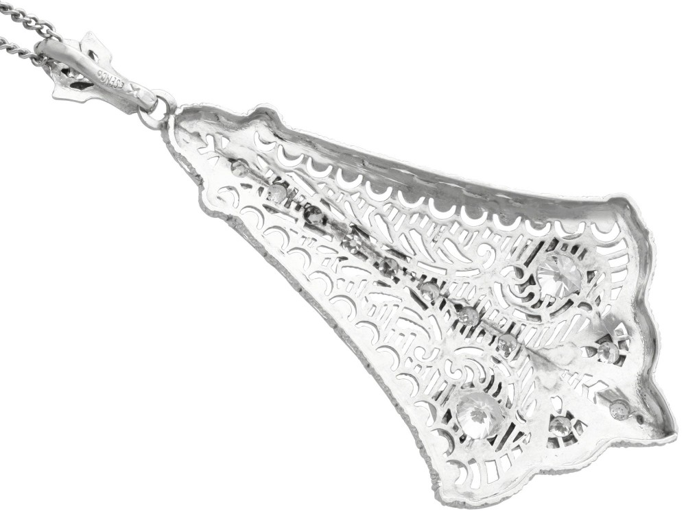 An Art Deco 14ct white gold pendant featuring geometric pierced filigree lattice work set with multiple diamonds suspended from a chain. View IX