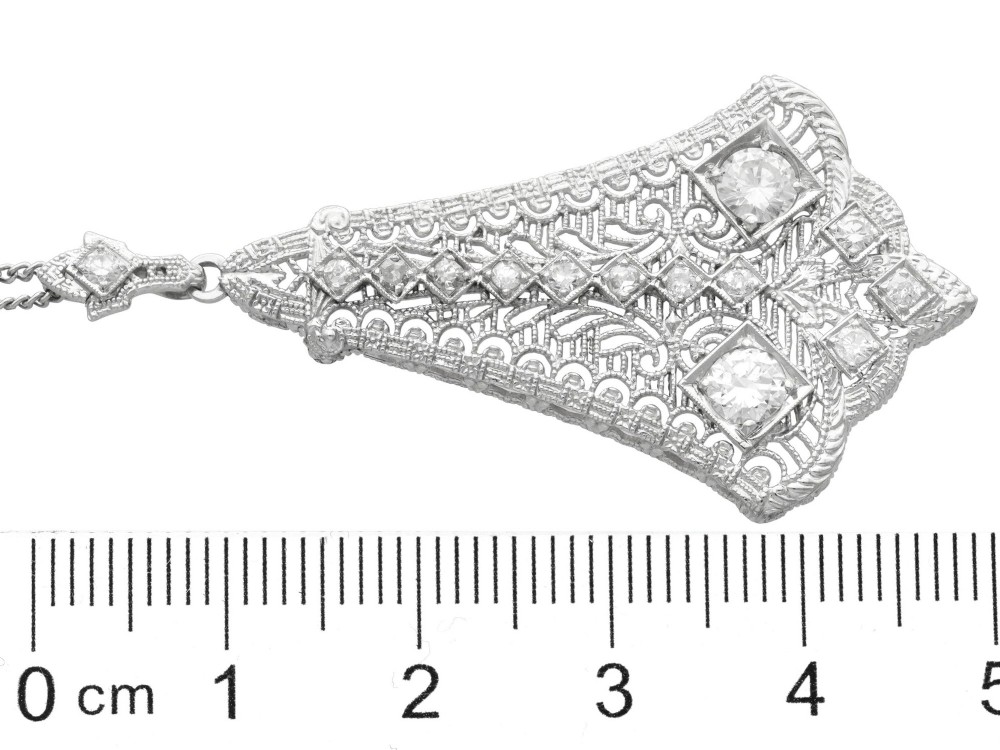 An Art Deco 14ct white gold pendant featuring geometric pierced filigree lattice work set with multiple diamonds suspended from a chain. View X