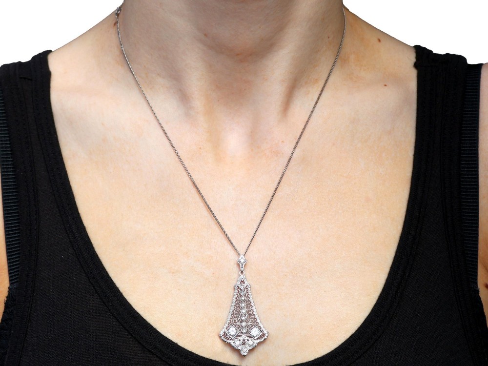 An Art Deco 14ct white gold pendant featuring geometric pierced filigree lattice work set with multiple diamonds suspended from a chain. View XI