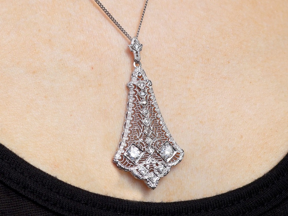 An Art Deco 14ct white gold pendant featuring geometric pierced filigree lattice work set with multiple diamonds suspended from a chain. View XII