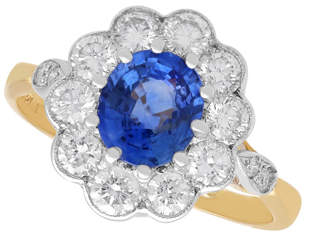 An 18ct yellow gold cluster ring featuring an oval blue sapphire surrounded by a halo of round diamonds set in platinum.