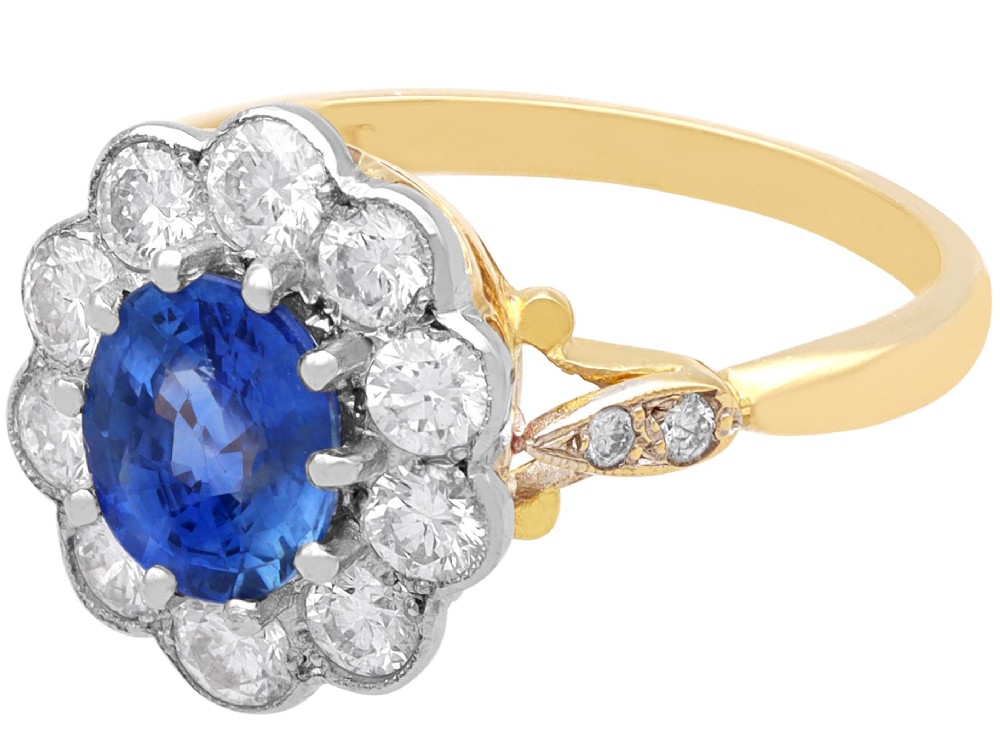 An 18ct yellow gold cluster ring featuring an oval blue sapphire surrounded by a halo of round diamonds set in platinum. View V