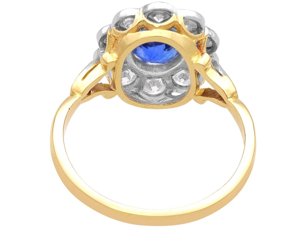 An 18ct yellow gold cluster ring featuring an oval blue sapphire surrounded by a halo of round diamonds set in platinum. View VI