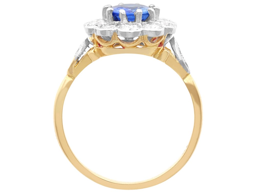 An 18ct yellow gold cluster ring featuring an oval blue sapphire surrounded by a halo of round diamonds set in platinum. View VII