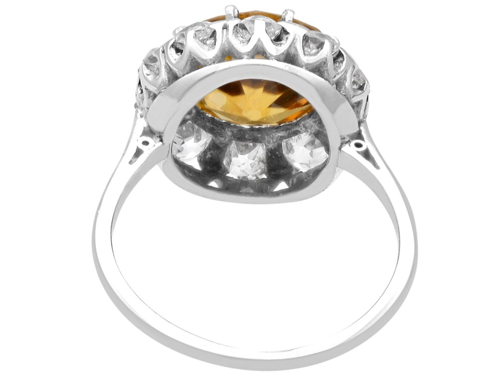 An antique Art Deco platinum ring featuring a central round orange zircon surrounded by a halo of claw-set diamonds. View IX