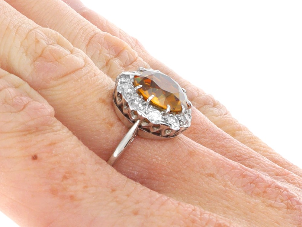 An antique Art Deco platinum ring featuring a central round orange zircon surrounded by a halo of claw-set diamonds. View XIII