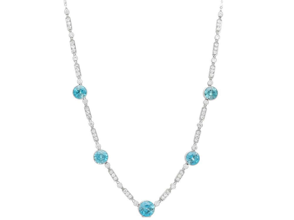 An Art Deco platinum chain necklace featuring five bezel-set round blue zircons separated by geometric diamond-set bar links.