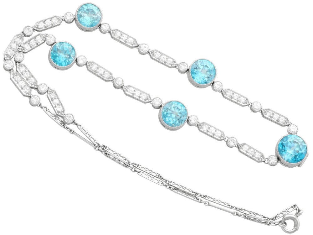 An Art Deco platinum chain necklace featuring five bezel-set round blue zircons separated by geometric diamond-set bar links. View VIII