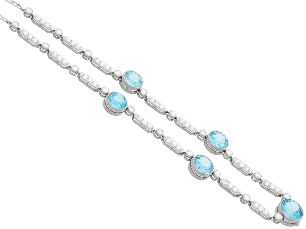 An Art Deco platinum chain necklace featuring five bezel-set round blue zircons separated by geometric diamond-set bar links. View IX