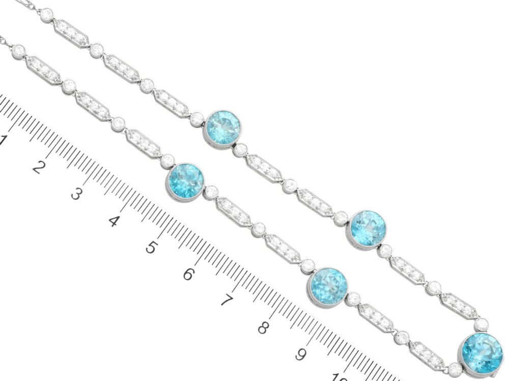 An Art Deco platinum chain necklace featuring five bezel-set round blue zircons separated by geometric diamond-set bar links. View XI