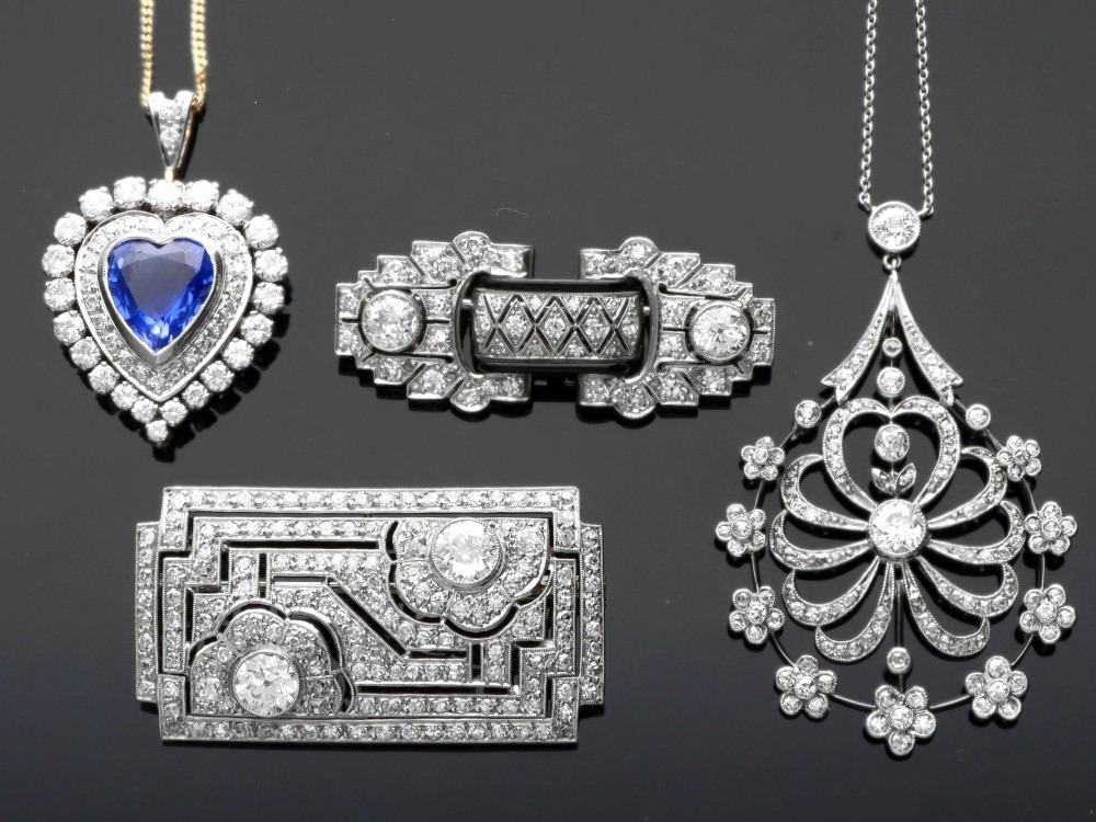 An antique Edwardian openwork platinum pendant set with diamonds in a teardrop silhouette with floral motifs, suspended from a fine chain. View III