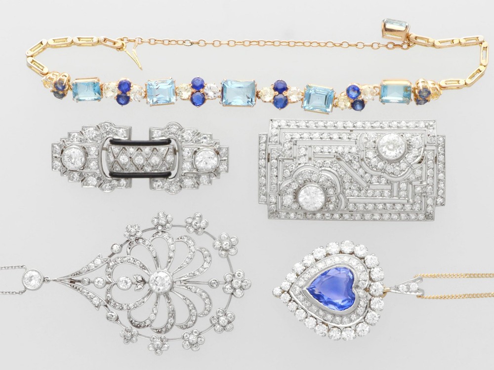 An antique Edwardian openwork platinum pendant set with diamonds in a teardrop silhouette with floral motifs, suspended from a fine chain. View IV