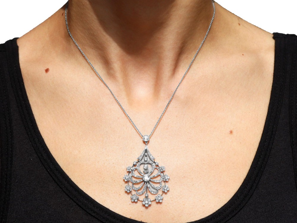An antique Edwardian openwork platinum pendant set with diamonds in a teardrop silhouette with floral motifs, suspended from a fine chain. View IX