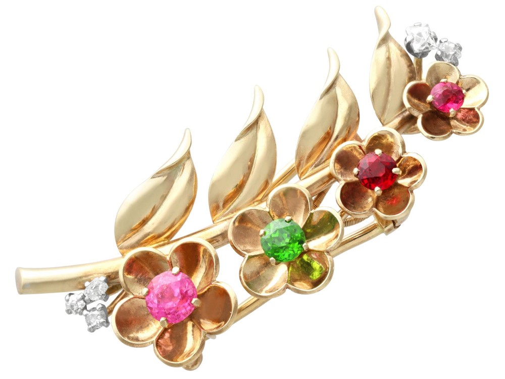 An antique 9ct yellow gold floral spray brooch featuring four carved flower heads set with colourful gemstones and diamond accents.