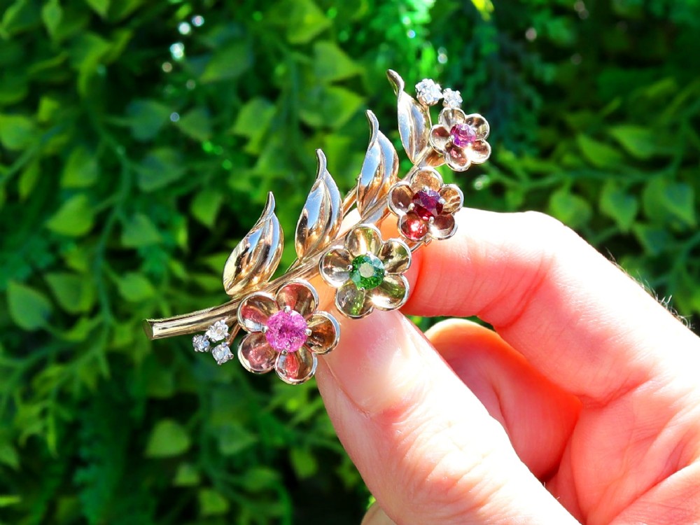 An antique 9ct yellow gold floral spray brooch featuring four carved flower heads set with colourful gemstones and diamond accents. View II
