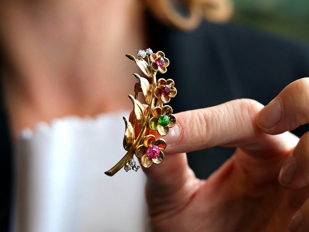 An antique 9ct yellow gold floral spray brooch featuring four carved flower heads set with colourful gemstones and diamond accents. View III