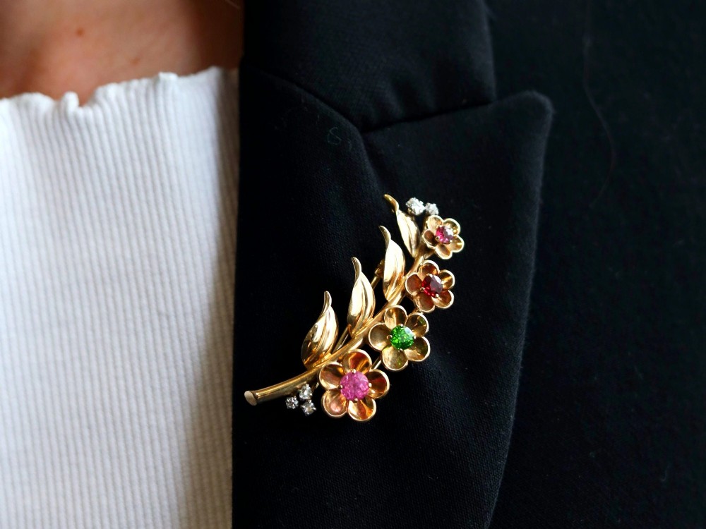 An antique 9ct yellow gold floral spray brooch featuring four carved flower heads set with colourful gemstones and diamond accents. View IV