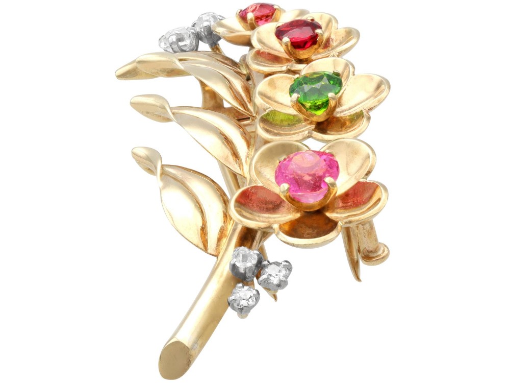 An antique 9ct yellow gold floral spray brooch featuring four carved flower heads set with colourful gemstones and diamond accents. View VI