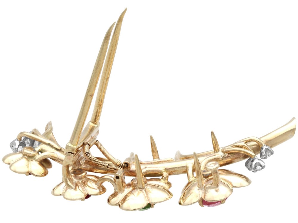 An antique 9ct yellow gold floral spray brooch featuring four carved flower heads set with colourful gemstones and diamond accents. View IX